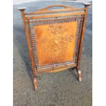 An arts & crafts oak fire-screen, with handle to shaped rail having square tapering columns with