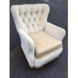 A button upholstered armchair with rounded back and loose cushion above a sprung seat, raised on