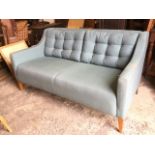 A Morgan 70s style upholstered beech sofa with padded back and shaped arms having button upholstered