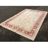 A Belgian wool rug woven with pale field of flowerheads on ivory ground, framed by frieze of