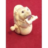 A carved bone novelty tape measure, the 56in tape issuing from mouth of carved bear like animal with