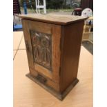 An art nouveau oak smokers cabinet having hinged top above a copper repoussé panelled door enclosing