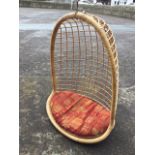 A 60s hanging love chair with arched canework canopy above an oval cushion seat. (46in)