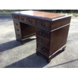 A reproduction mahogany kneehole desk, the rectangular moulded top with gilt tooled skiver having