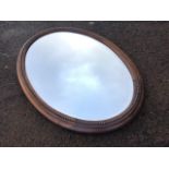 An Edwardian oval oak framed mirror, the bevelled plate in moulded bead-mounted frame. (31.75in x