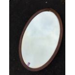 An oval mahogany framed mirror with bevelled plate. (32in x 21in)