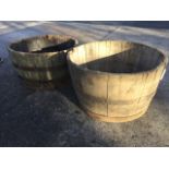 A near pair of large oak barrel garden tubs, the staves bound by metal strap bands. (29in x 17in) (