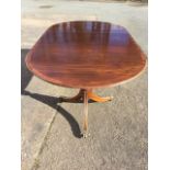 A Georgian style twin pedestal mahogany dining table with leaf, the crossbanded rounded top with