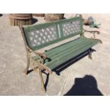 A garden bench with twin latticework panelled back above a slatted seat, with cast iron scrolled