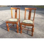 A pair of oak chairs with rounded back rails above routed splats, the drop-in tapestry woolwork