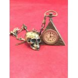 A brass linked albert chain mounted with triangular masonic pocket watch and skull with opening