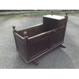 An antique oak cradle, with dowel jointed fielded panelled box on shaped rockers, the cornerposts