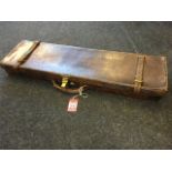 A rectangular leather gun case with baize lined interior, having brass mounts and leather straps. (