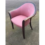 An upholstered armchair with rounded frame above a sprung seat, raised on rectangular tapering