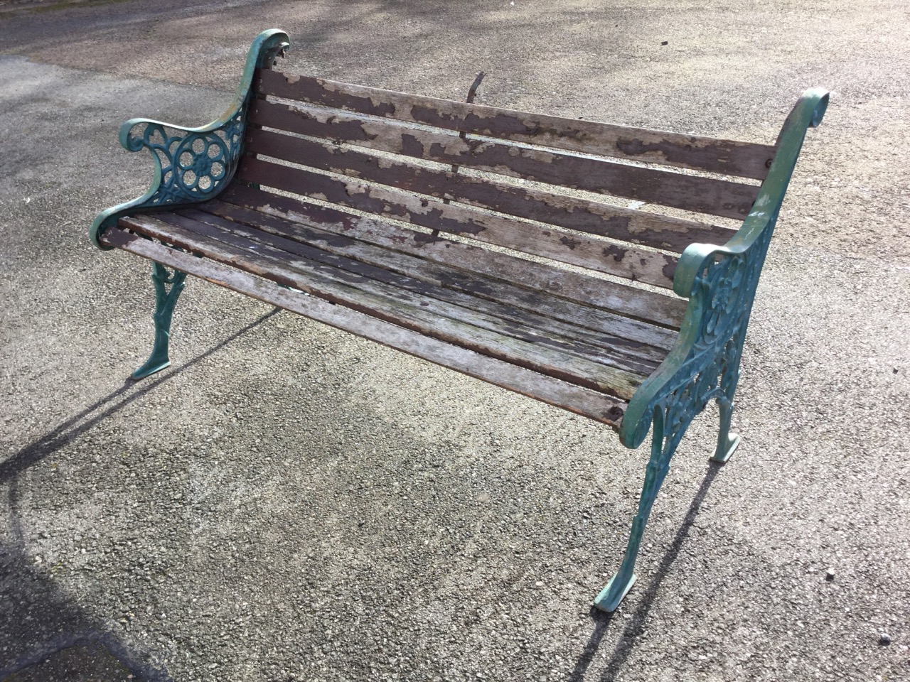 A cast iron garden bench with hardwood slatted back & seat, the ends with pierced roundels beneath