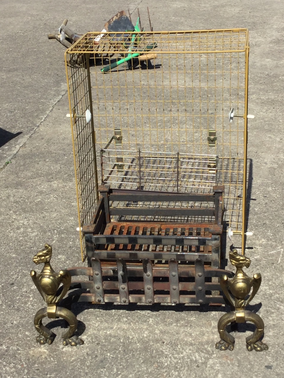 A wrought iron grate front with riveted trellis flanked by brass winged stylised birds on