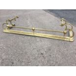 A late Victorian brass fender, the moulded curb with three ball mounts supporting tubular rail,