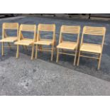 A set of five folding chairs with slatted backs and seats raised on rectangular legs joined by