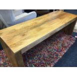 A rectangular contemporary hardwood coffee table on plain supports. (55in x 19.75in x 20in)