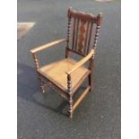 A late Victorian stained armchair with bobbin turned columns and scalloped scroll carved back rail