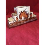 An art deco style desk tidy modelled with stepped rectangular compartments, enamelled with beaked