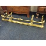 A Victorian brass fender with tubular rail on squat columns with finials, above a moulded curb;