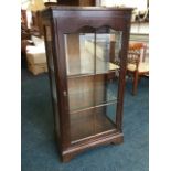 An oak display cabinet with shaped astragal glazed door enclosing glass shelves, framed by ribbed