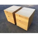 A pair of contemporary oak filing cabinets, each with two drawers, raised on casters. (17in x 21.5in