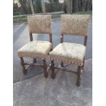 A pair of Carolean style oak side chairs with brass studded tapestry style upholstery, raised on