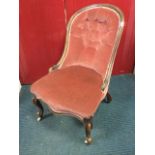 A Victorian button upholstered spoonback chair with scrolled carving, having sprung upholstered