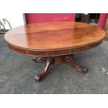 An oval early Victorian mahogany dining table, the top with ribbed edge and plain frieze supported