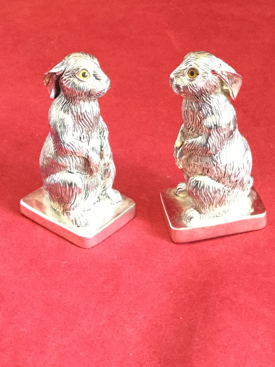 A pair of silver plated hare salt & pepper pots, the animals alertly seated on rectangular