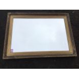 A rectangular mirror in press moulded gilt frame. (22.5in x 31.5in)