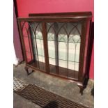 A bowfronted mahogany display cabinet, with upstand to moulded top above gothic astragal glazed