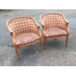 A pair of bergére style armchairs, with moulded rounded backs with brass studding having scrolled