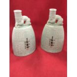 A pair of Chinese celadon glazed porcelain flasks with dragon handles and tubular necks above