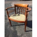 A carved mahogany captains chair with rounded back and scrolled arms on spindles framing a curved