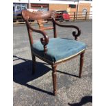 A George IV mahogany open armchair with scroll carved back rail centering on flowerheads above a