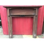 A stained Edwardian chimneypiece with moulded cornice above an arched apron and bowfronted shelf