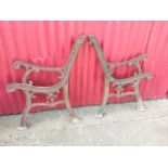 A pair of cast iron bench ends with scrolled arms and frames, supported on channelled sabre legs. (