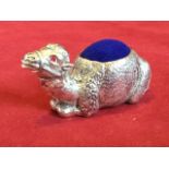 A silver plated pin cushion cast as a seated camel having inlaid ruby eyes, the hump or back with