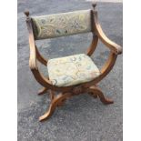 A mahogany Glastonbury chair with floral needlework back & seat, the scrolled arms carved with