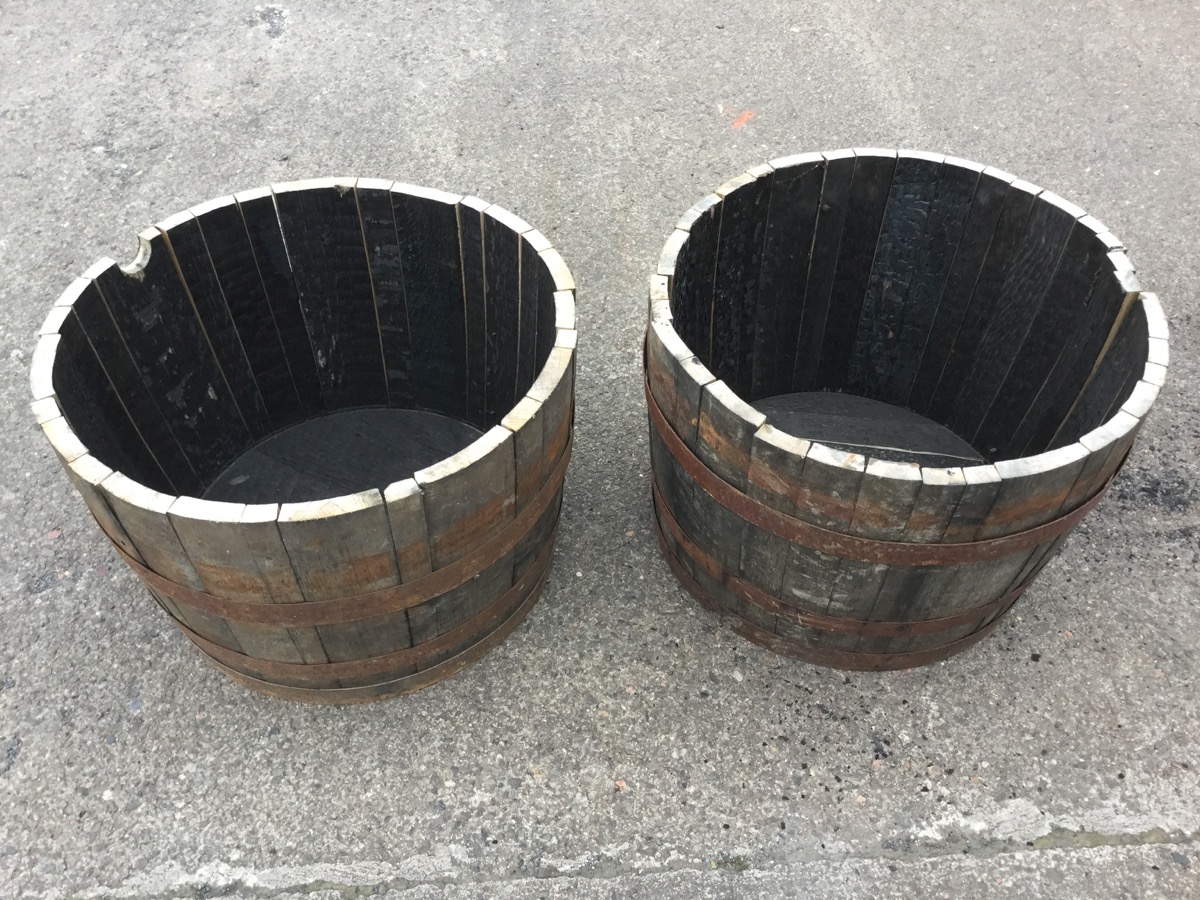 A pair of oak garden barrel tubs, each with staves bound by three riveted metal strap bands. (17in x