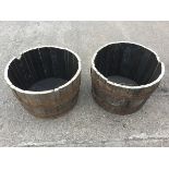 A pair of oak garden barrel tubs, each with staves bound by three riveted metal strap bands. (17in x