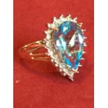 A 9ct gold blue topaz & diamond ring, the pear shaped claw set topaz stone framed by diamonds,