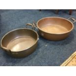 A large circular copper bowl with rolled rim, riveted with carrying handles; and another similar. (