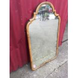 A walnut framed mirror with arched plate in cushion moulded frame, carved with foliate motif to
