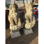A pair of composition stone lions sejant, the beast raised displaying heraldic shields on square