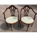 A pair of late Victorian mahogany saloon armchairs, having arched shaped backs above gothic