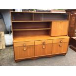 A 70s teak dresser with sliding glass doors above an open bookshelf and drop-down compartment, the